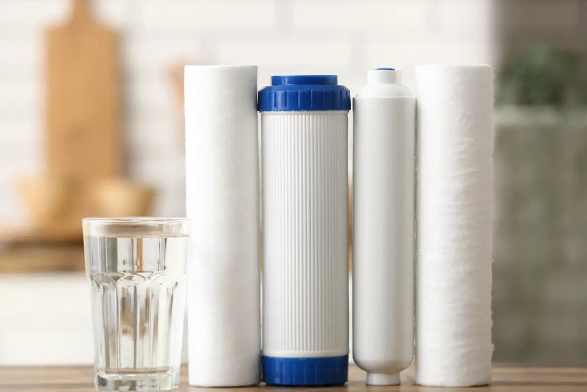 Weiße zylindrische Wasserfilterpatronen mit blauen Kappen und gerippten Oberflächen, eine mit einem texturierten weißen Gehäuse.